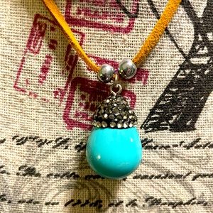 Adjustable faux suede choker with elegant turquoise teardrop pendant.